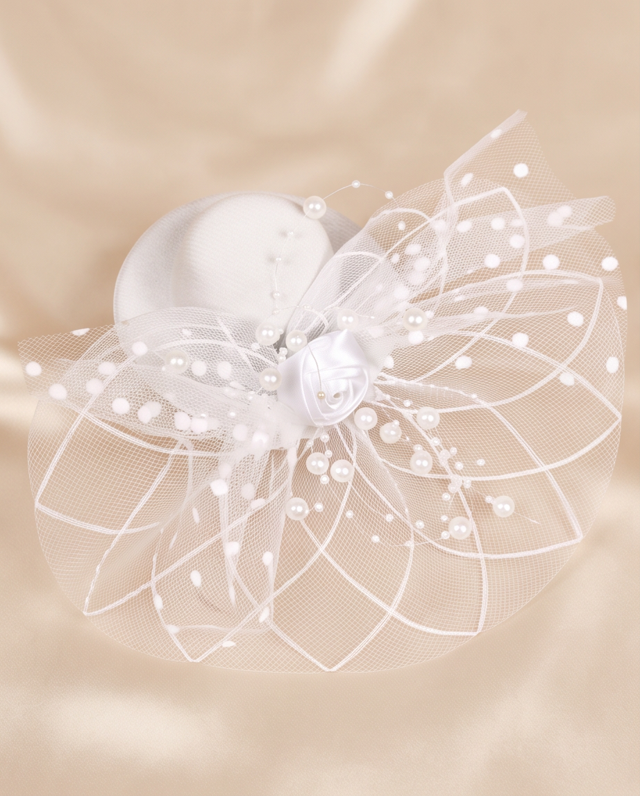 White pearl and rose fascinator with layered tulle netting flat lay on cream satin background