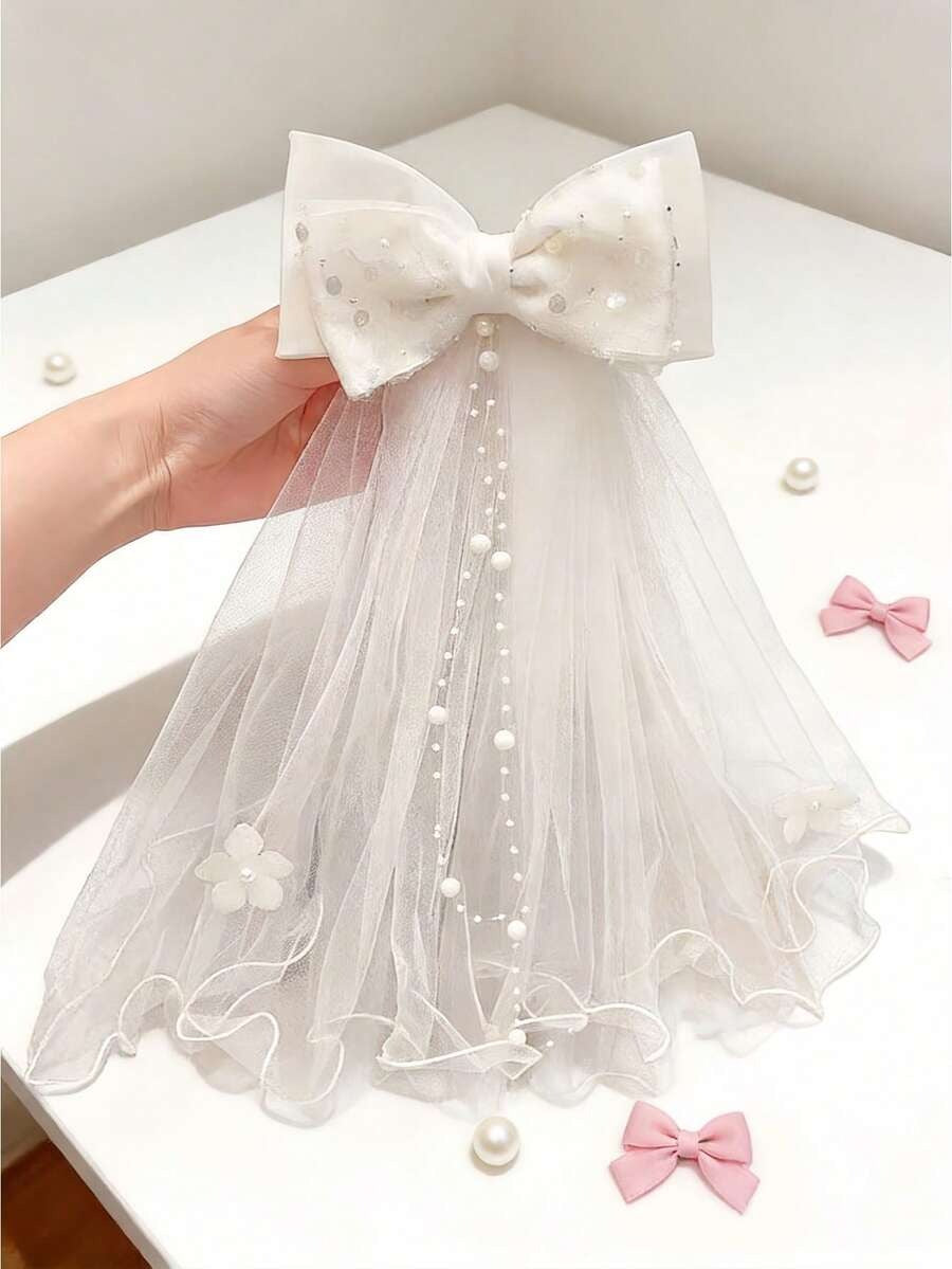 White pearl dot tulle bow communion veil with pearl chain trail and 3D flower appliqués, held up showing full detail