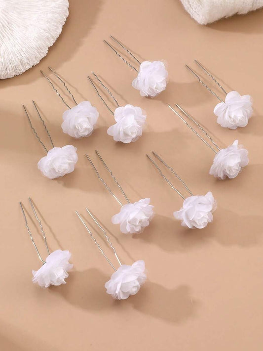 10 white chiffon rose hair pins scattered on beige background showing soft layered petals
