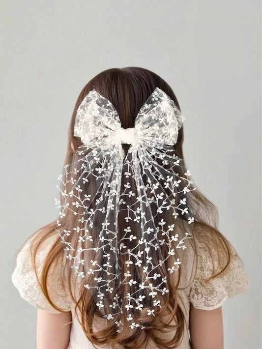 Person wearing a large decorative bow in their hair against a plain background