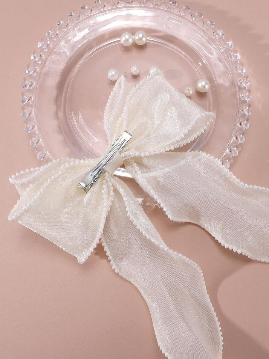 White bow hair clip with decorative elements on a pink background