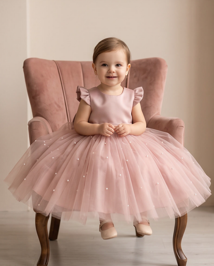 Close-up back view of oversized satin bow on blush pink flower girl dress