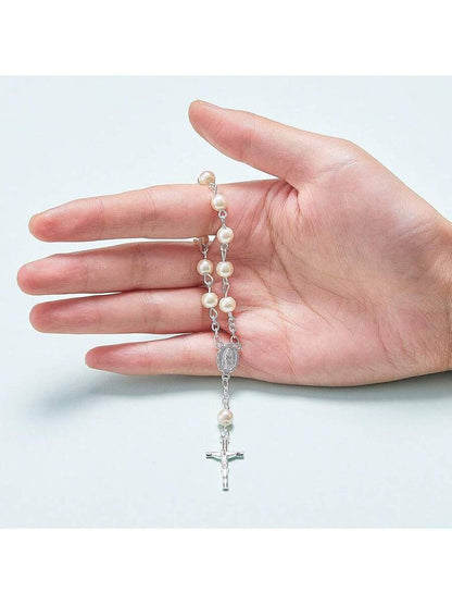 White pearl rosary bracelet with silver Miraculous Medal and crucifix on white satin fabric, elegant flat lay