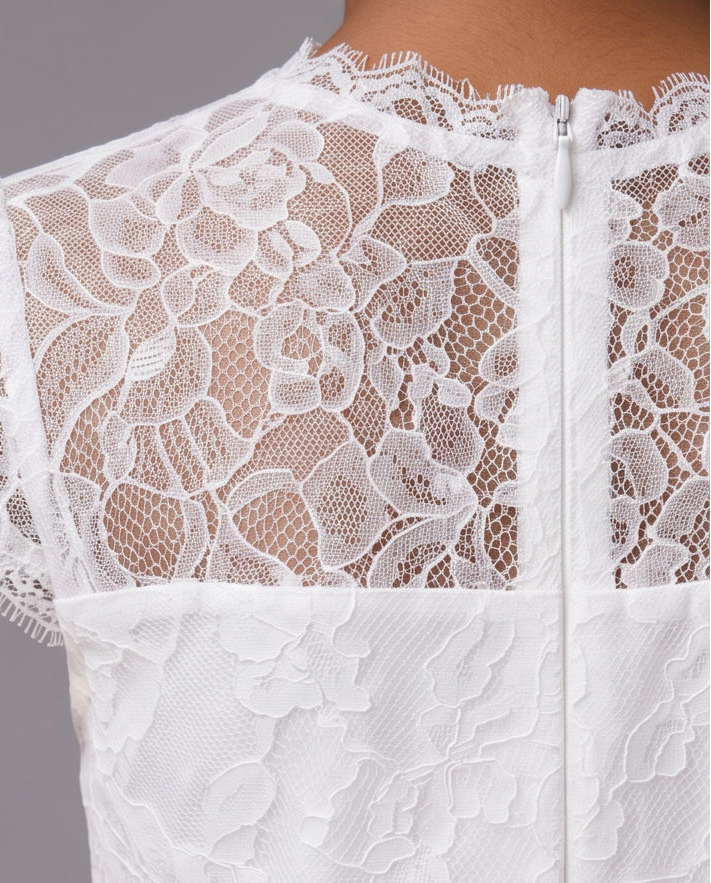 Close-up of the back of a white lace dress with floral lace overlay, short lace sleeves, and a central zipper, shown against a plain gray background.