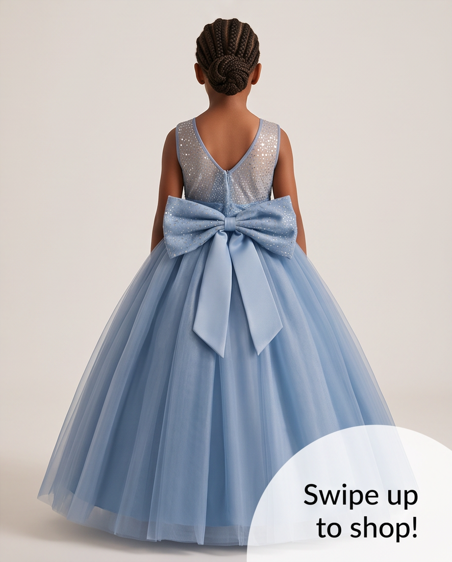 A young girl viewed from behind wearing a sleeveless light blue tulle ball gown with a large bow at the back waist and a sparkly sequined V-neck bodice. The photo is on a plain warm beige studio background with a white circular overlay reading 'Swipe up to shop!'.