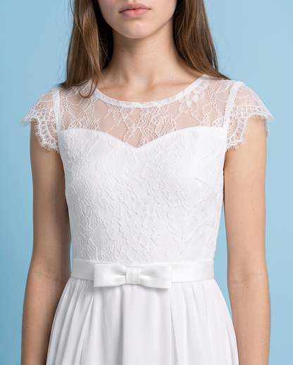 A woman wearing a white lace and satin dress against a light blue background.