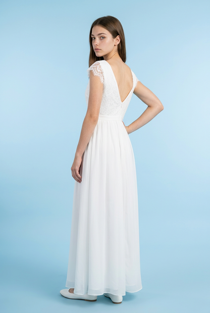 A woman modeling a white floor-length dress from the back, featuring a deep V-neckline, lace cap sleeves, and a flowing chiffon skirt, set against a solid light blue studio background.