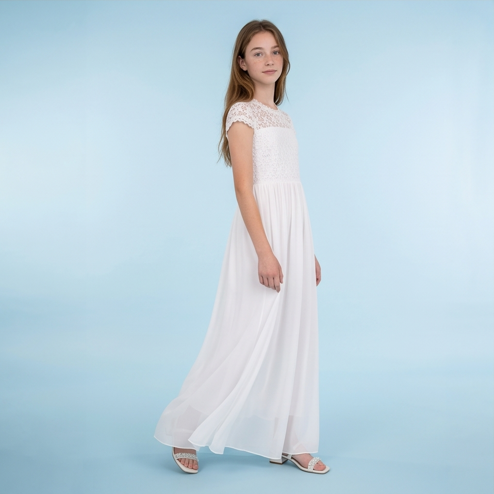 A young girl modeling a long white maxi dress with a lace bodice and cap sleeves, standing against a light blue studio background.
