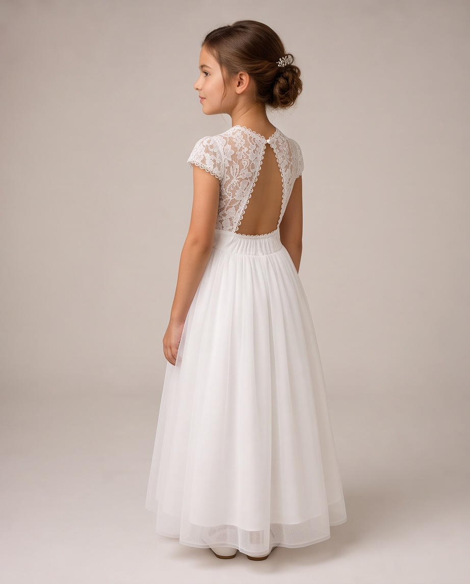 A young girl shown from the back wearing a white formal dress with lace cap sleeves, a sheer lace open back, and a full tulle skirt, photographed against a plain light beige studio background.