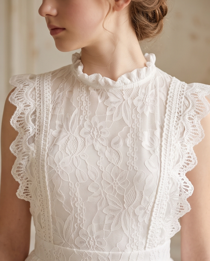 Close-up of a woman wearing a white lace dress with a ruffled high neck, cap sleeves with scalloped lace trim, and floral lace detailing.