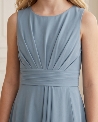 Close-up of a sleeveless dusty blue dress with a gathered waistband and draped bodice, shown on a model.