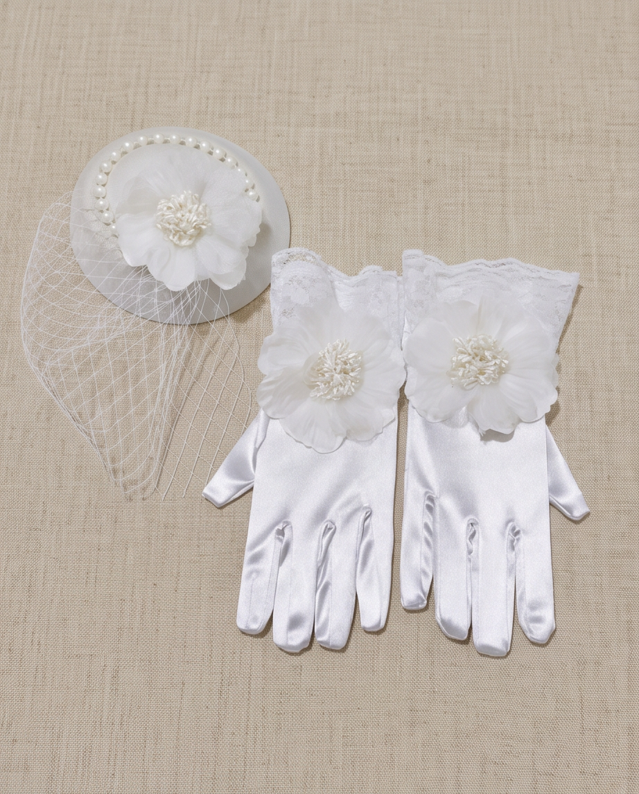 White communion 2-piece set: pearl birdcage fascinator and white satin gloves with lace cuff and flower detail, flat lay on linen