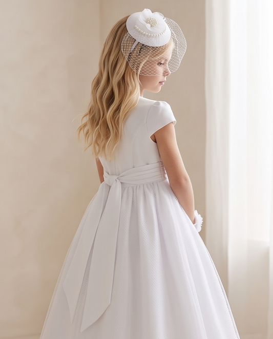 Girl wearing white pearl birdcage fascinator with flower detail and birdcage netting, back view in white communion dress