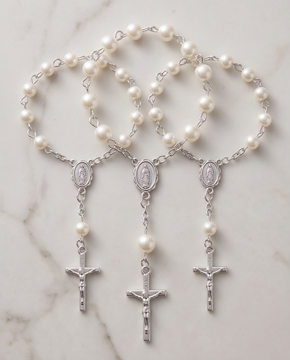 Hand holding white pearl rosary bracelet with silver Miraculous Medal and crucifix, close-up view