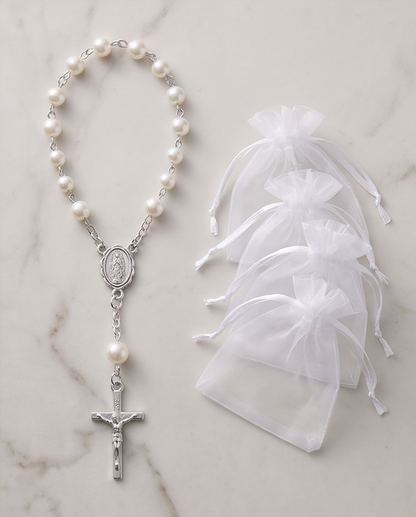 Three white pearl rosary bracelets with silver Miraculous Medal and crucifix on marble background