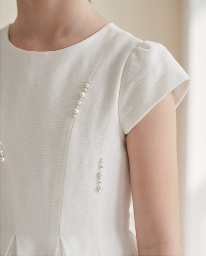 Girl wearing white pearl detail communion dress smiling three quarter view