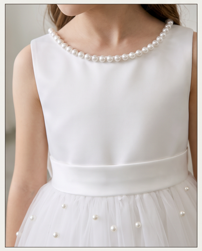 Girl wearing white pearl neckline tulle dress full length front view holding white bouquet