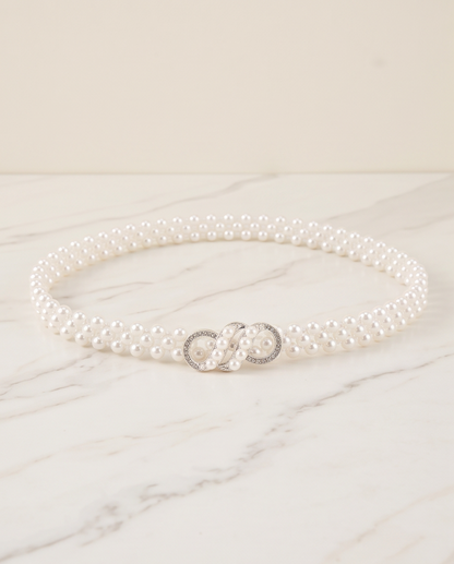 White pearl-look infinity clasp communion belt arranged on a marble background