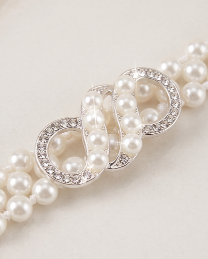 Close-up of the sparkling infinity clasp on a white pearl-look communion belt