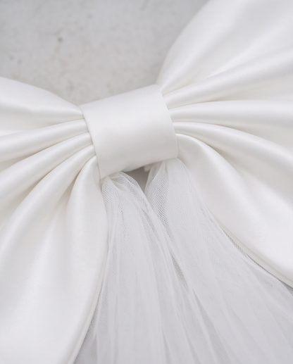 Close-up of the satin centre of an oversized white bow with tulle
