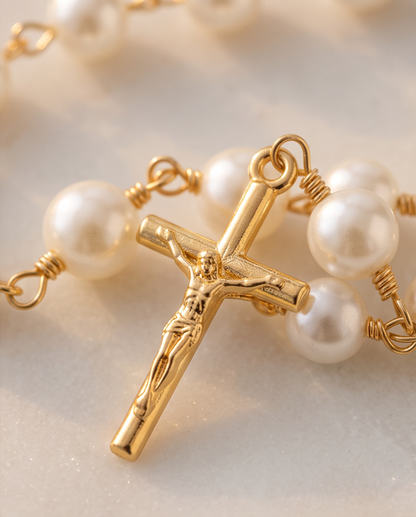Close-up of gold-tone Miraculous Medal and crucifix on pearl rosary bracelet