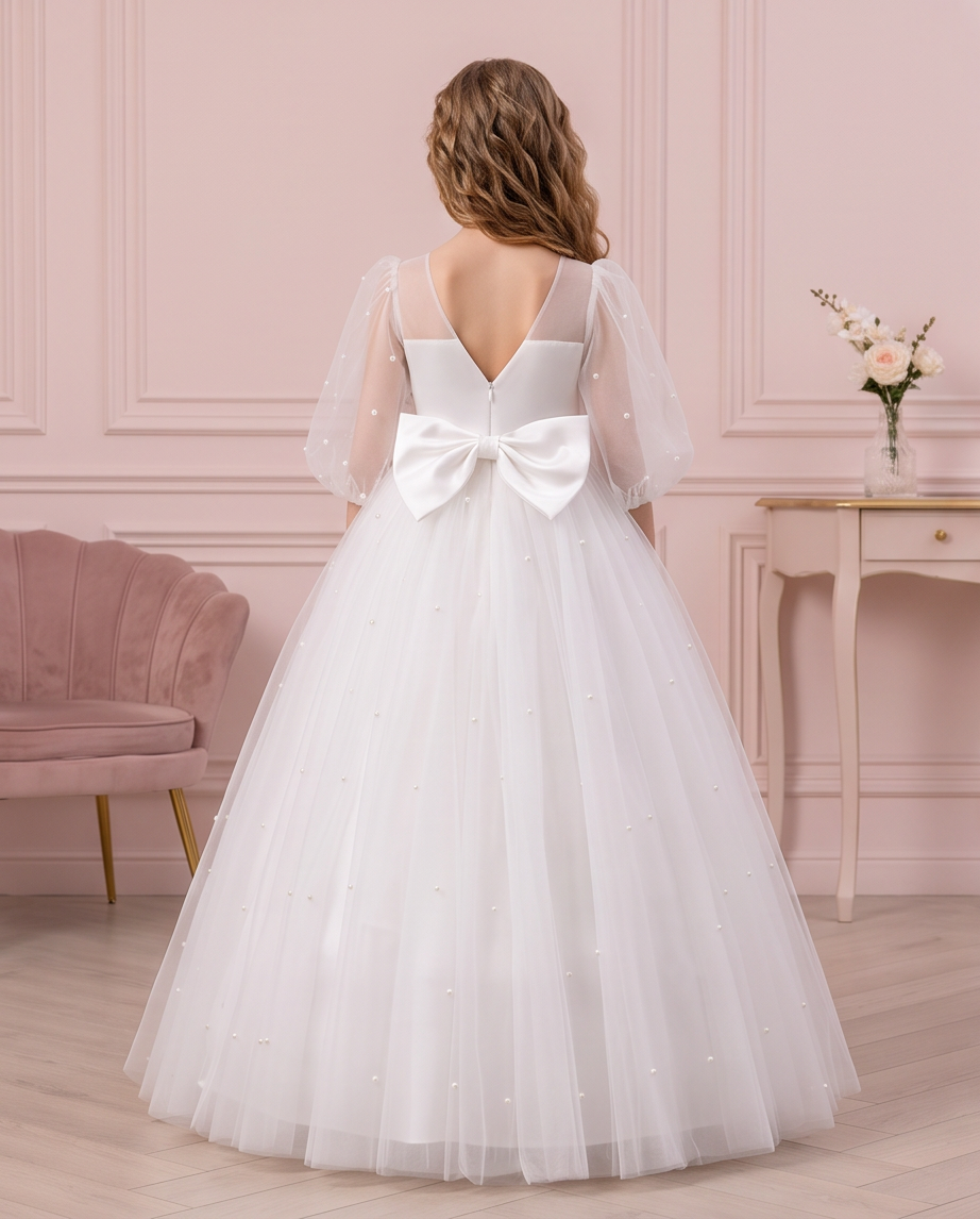 Full back view of the Pearl Reverie dress showing its V-shaped back, large white bow and pearl-detailed skirt.