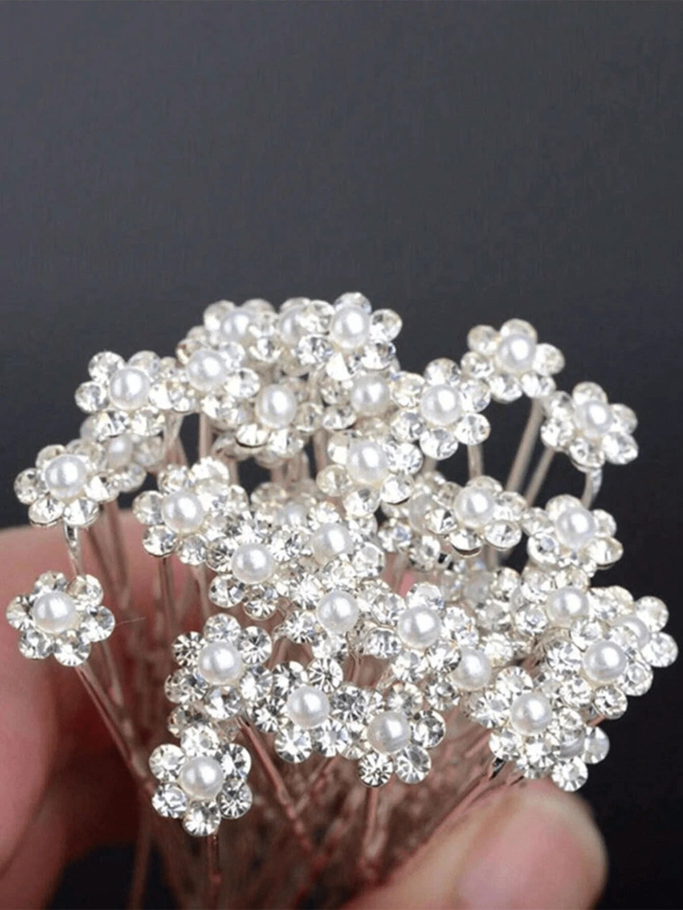 Silver pearl and rhinestone flower hair pins arranged on black background, product flat lay view