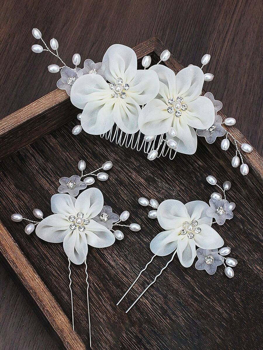 White organza flower hair comb and 2 hair pins with pearl sprays displayed on wooden tray, close-up detail view