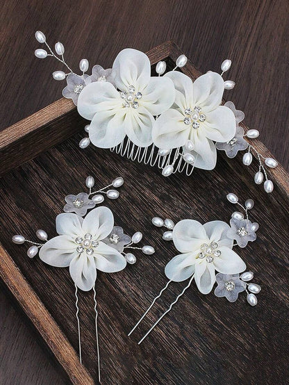 White organza flower hair comb and 2 hair pins with pearl sprays displayed on wooden tray, close-up detail view