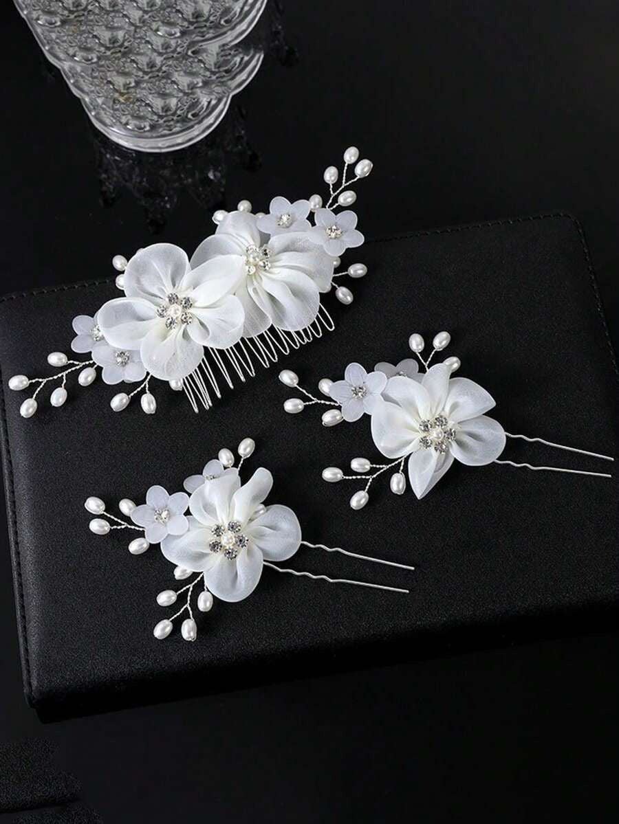 White organza flower hair comb and 2 hair pins with rhinestone centres and pearl spray branches on black background