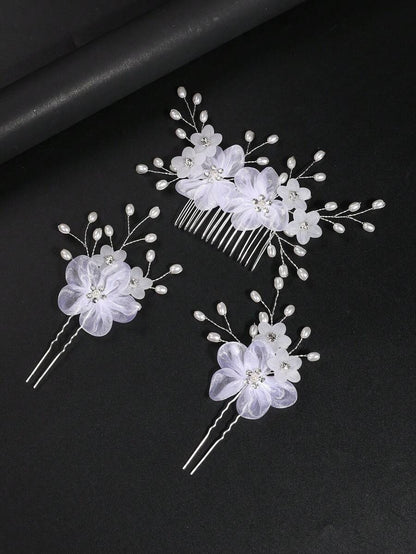 White organza flower hair comb and 2 hair pins with pearl sprays on dark background, top-down flat lay view