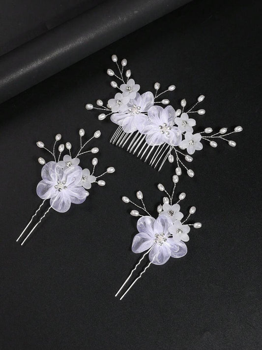 White organza flower hair comb and 2 hair pins with pearl sprays on dark background, top-down flat lay view