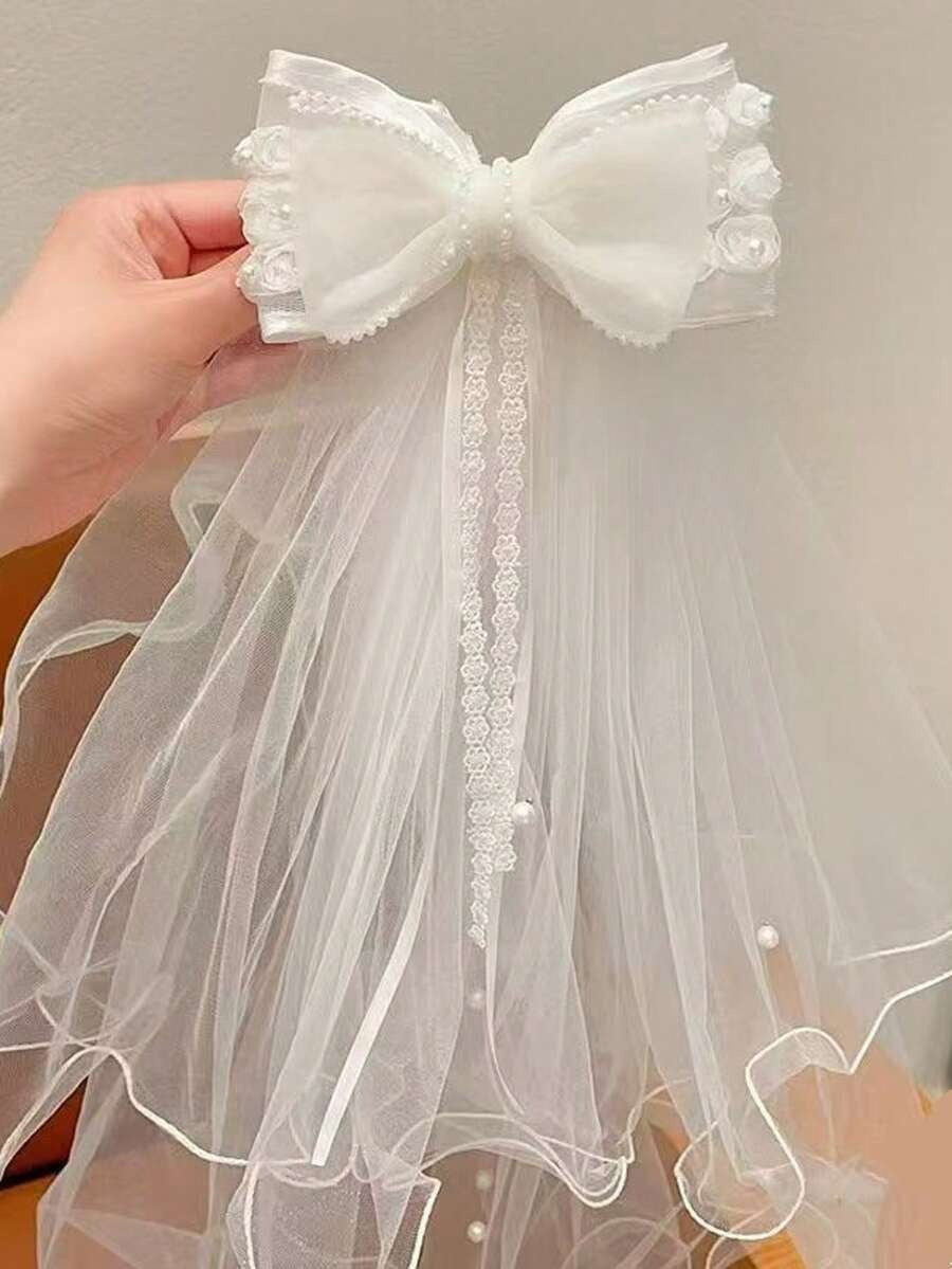 White ruffle organza bow communion veil with lace centre ribbon, held up against plain background