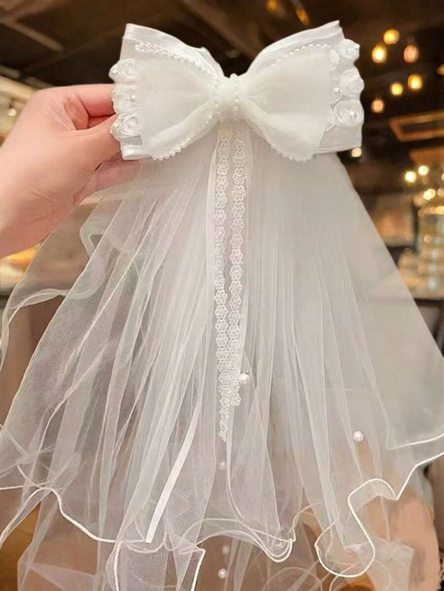 White ruffle organza bow communion veil with lace centre ribbon and pearl trim, held up showing full detail