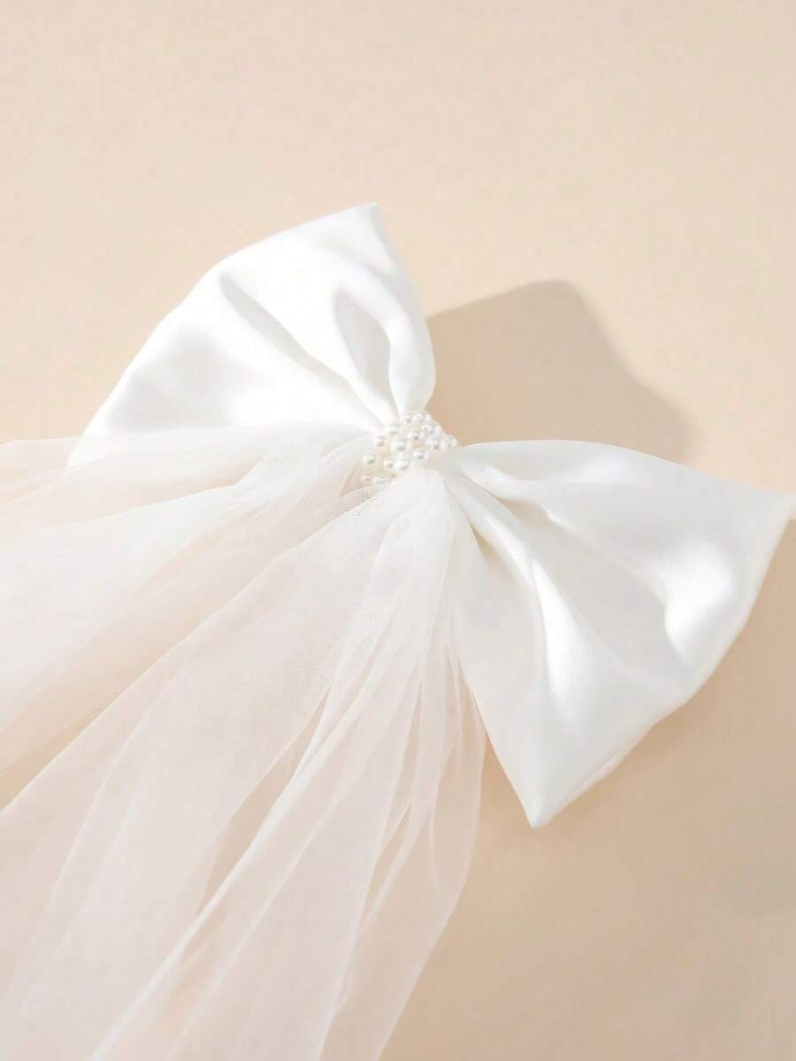 Close-up of white satin bow with pearl centre detail on communion veil