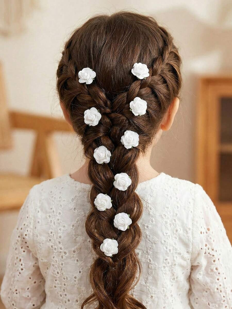 Girl with braided hair styled with white chiffon rose hair pins throughout braid, back view in white dress