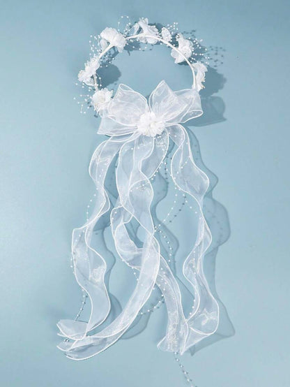 White floral crown communion veil with organza bow and pearl ribbon on blue background, full length view