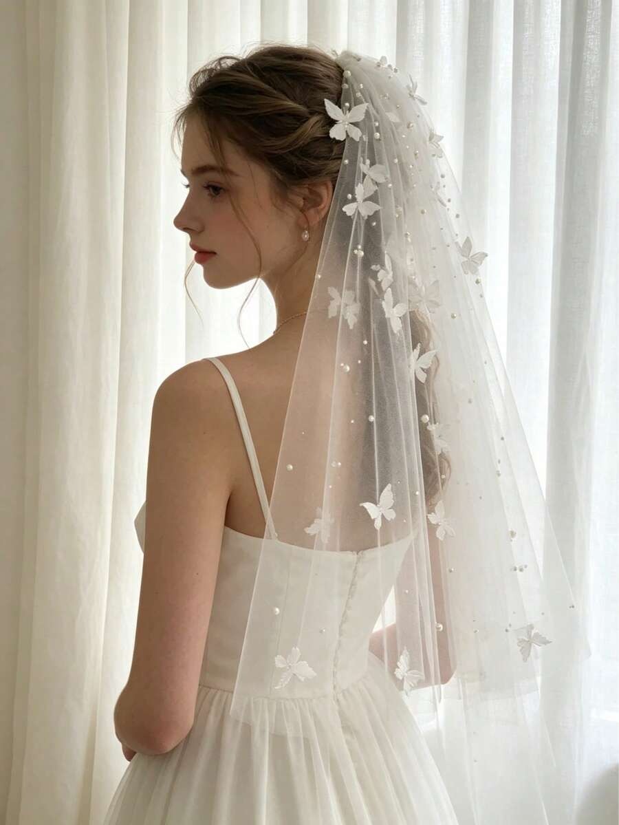 White butterfly communion veil with pearl dots scattered on soft tulle, flat lay view