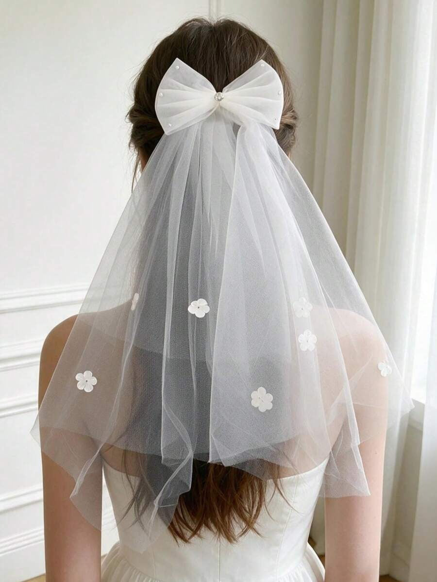 Girl wearing white tulle bow communion veil with floral appliqués, back view showing elegant drape and large bow