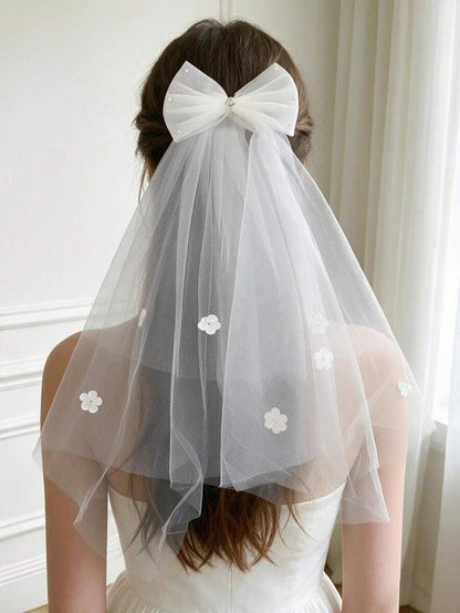 Girl wearing white tulle bow communion veil with floral appliqués, back view showing elegant drape and large bow