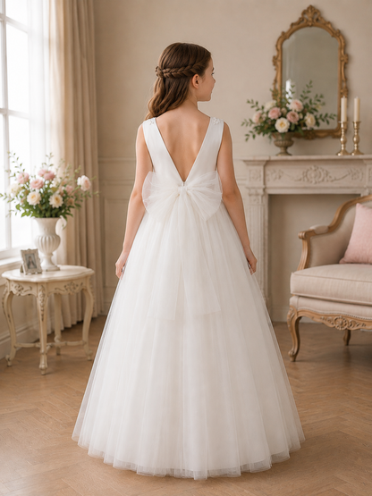 Girl in a white wedding dress standing in a elegant room with floral arrangements and a fireplace.