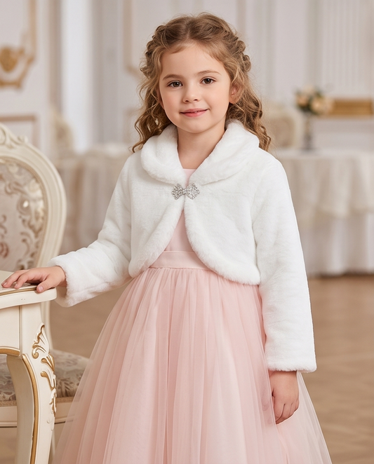Young girl in a white fur shrug and pink dress standing in an elegant room.