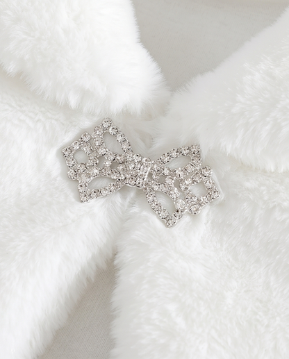 Silver bow-shaped brooch with clear gemstones on a white fur background
