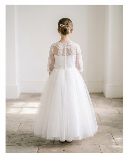White lace dress worn by a person standing in a softly lit room.