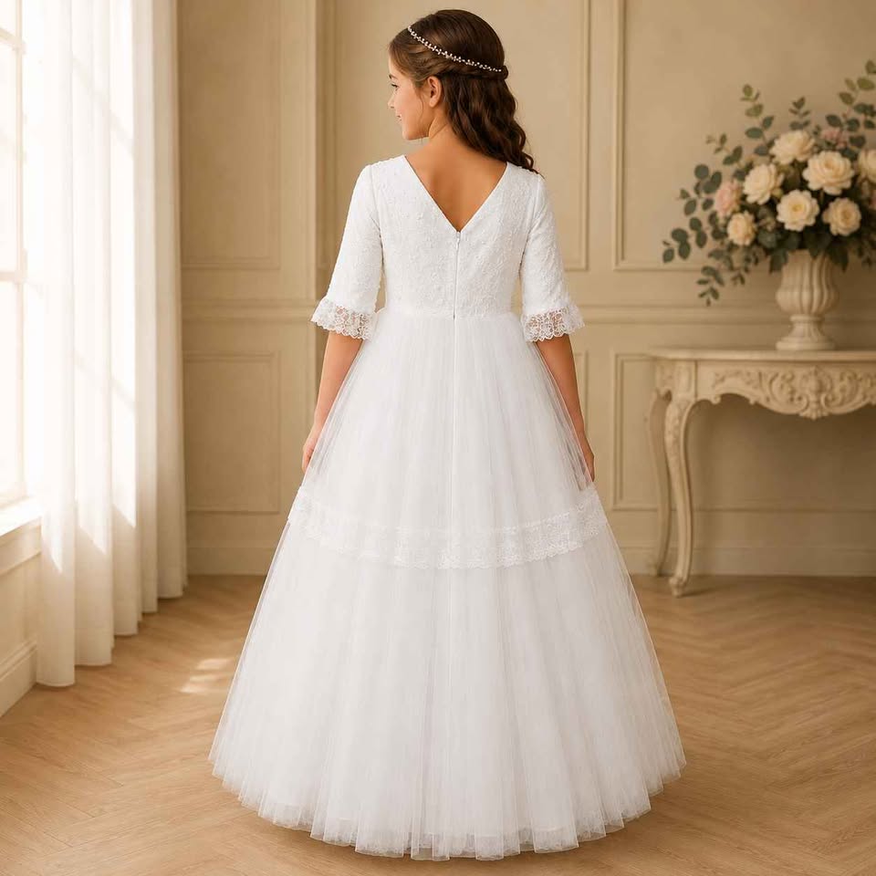 Girl in a white wedding dress standing in a room with floral decorations.