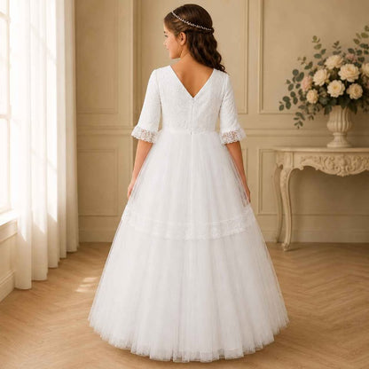Girl in a white wedding dress standing in a room with floral decorations.