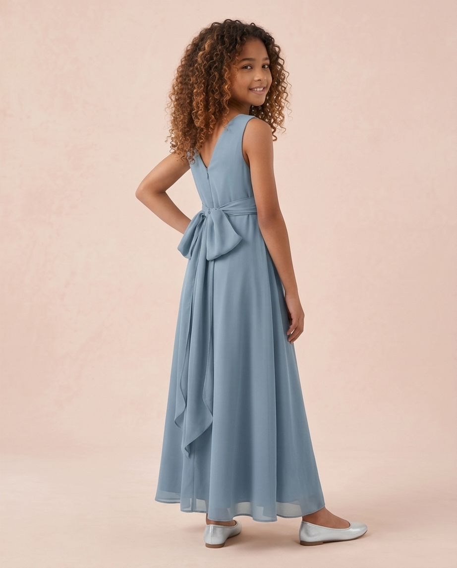 Young girl wearing a light blue dress with a bow detail on a pink background