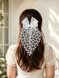 Person with long hair wearing a decorative hair scrunchie in a softly lit room.