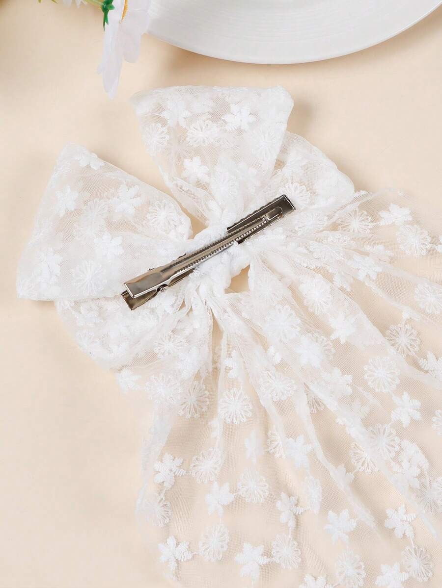 White lace bow with a hair clip on a beige background