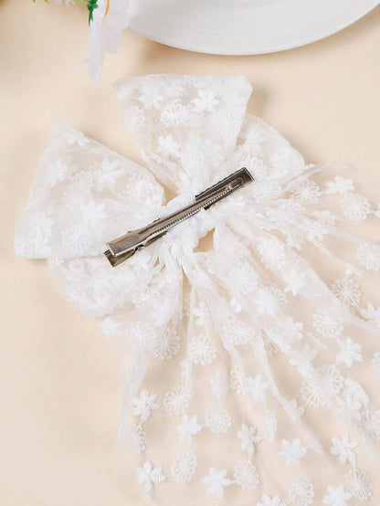 White lace bow with a hair clip on a beige background